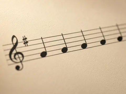 A close-up of a printed music staff with a treble clef and notes on cream paper